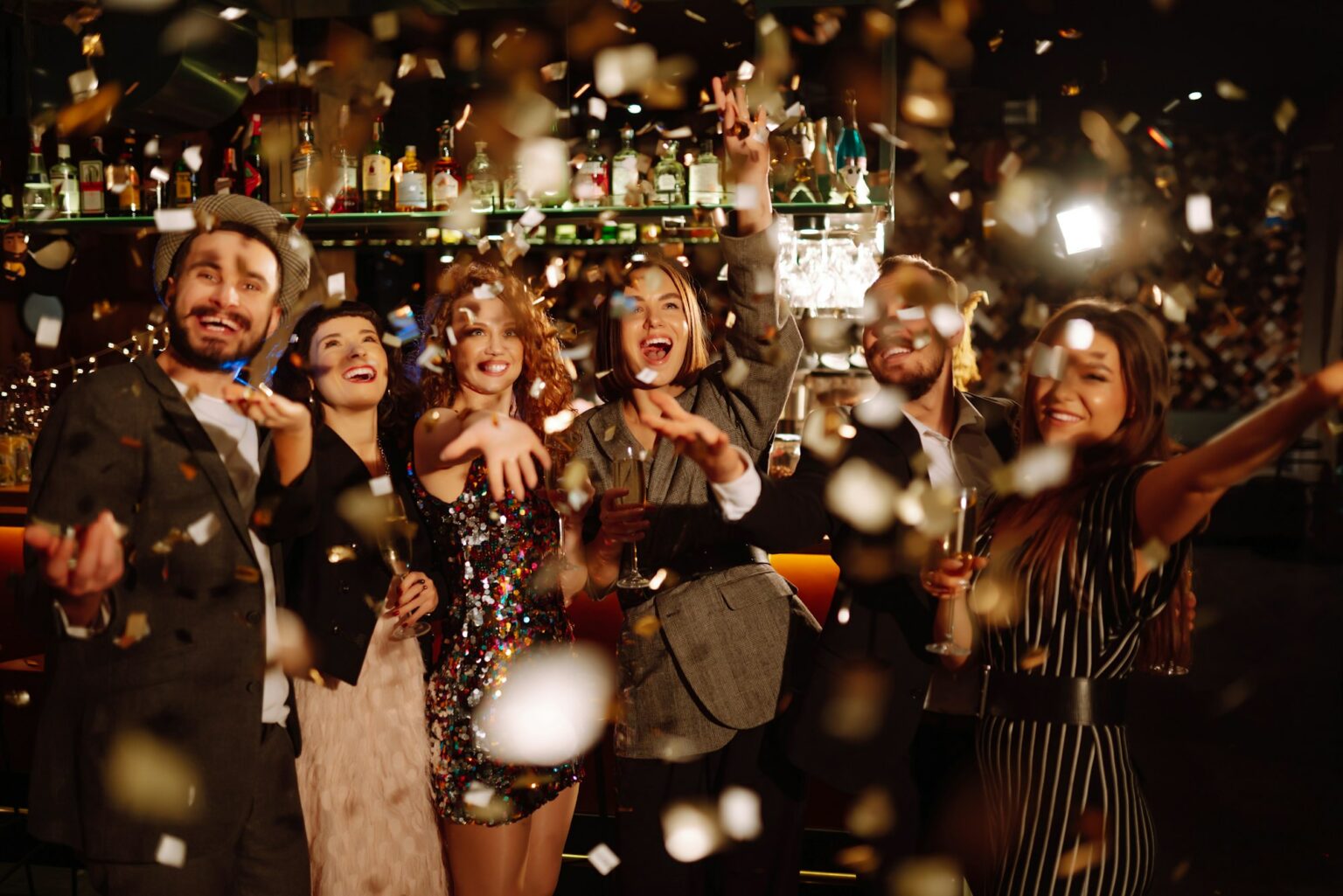 Comment s’habiller pour une soirée ? Happy friends throwing confetti and jumping while enjoying party Confetti is fun. Party, celebration