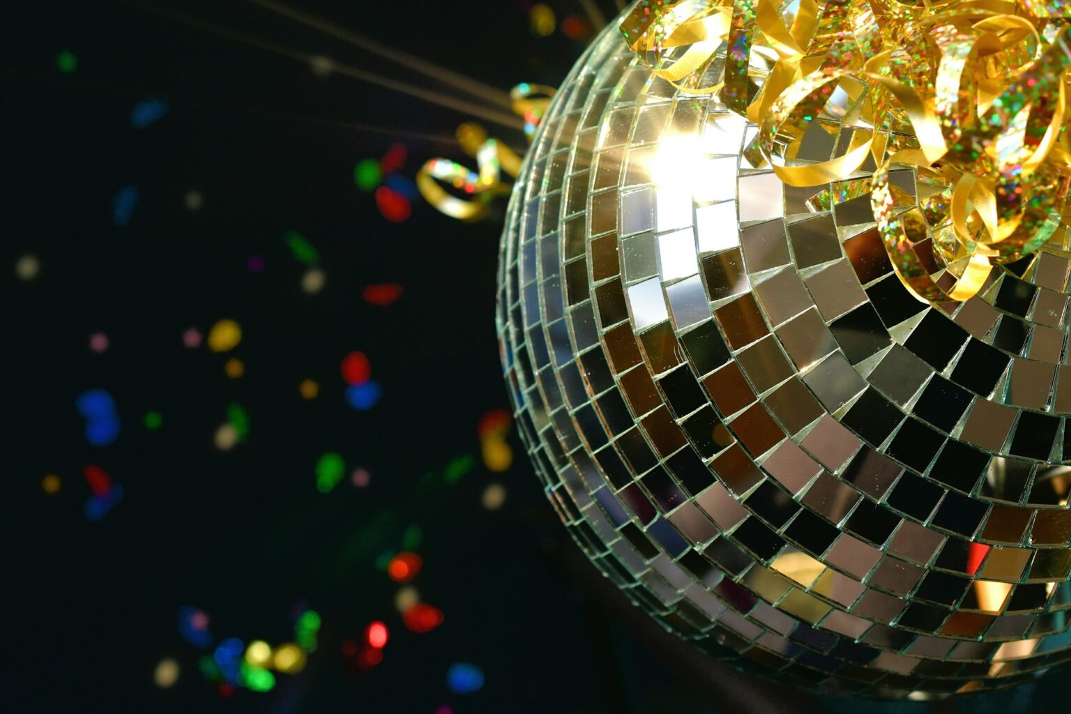 Shiny retro disco ball sparkling in the light with glittery ribbon and colorful confetti