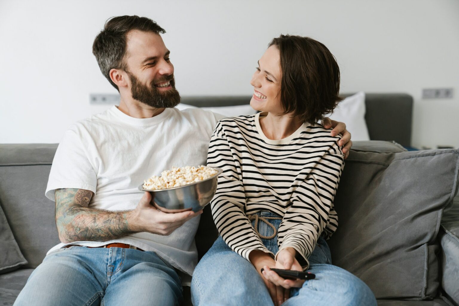 15 comédies cultes à (re)voir pour une soirée sans prise de tête Happy young white couple watching TV