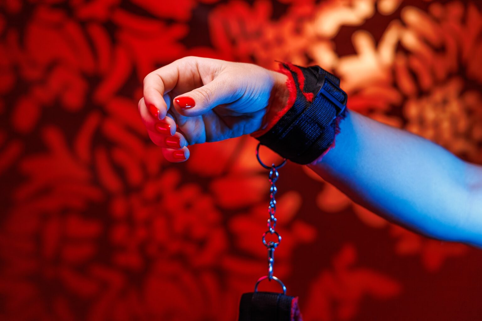 Les meilleurs sites de rencontre BDSM en 2025 Soft BDSM handcuffs adorn a womans hands with alluring red nails
