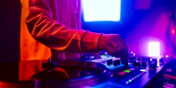 Hands of a DJ creating and regulating music on dj console mixer at club concert