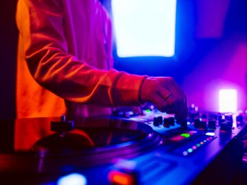 Hands of a DJ creating and regulating music on dj console mixer at club concert